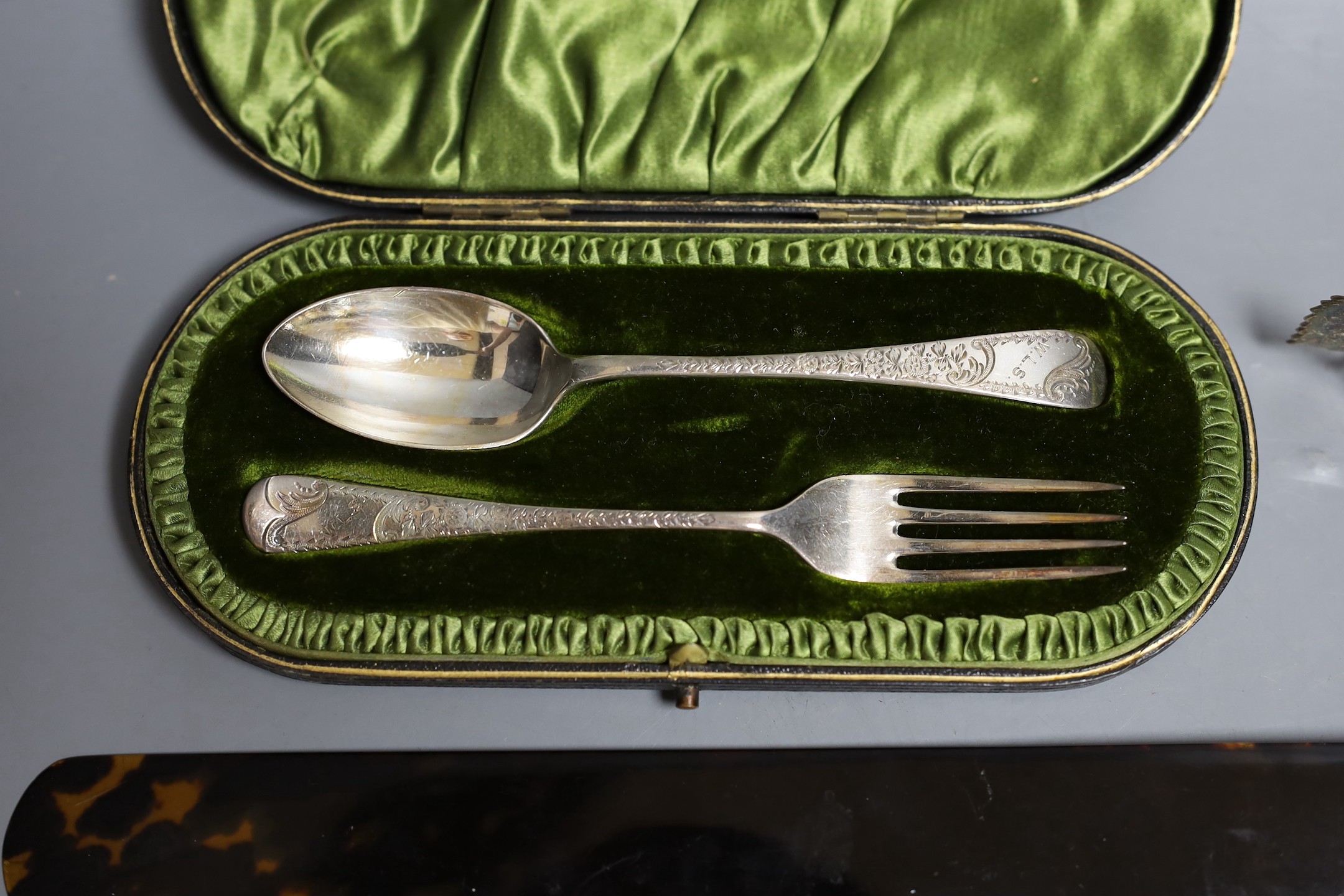 A late Victorian repousse silver mounted tortoiseshell page turner (chip), 39.6cm, a silver rattle, a silver the Irish Times pin tray, 800 standard model of a rose and a cased silver christening pair.